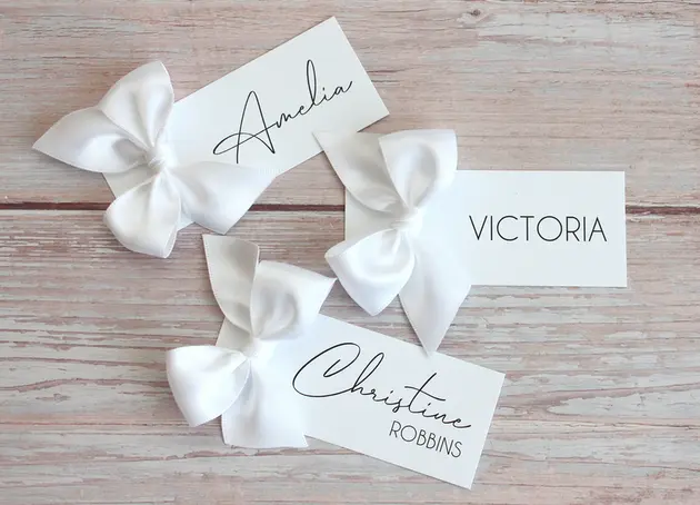 Modernas baltas galda kartītes ar viesu vārdiem un satīna 
banti. Minimālistisks dizains, kas piešķir galda noformējumam tīru, 
svinīgu un gaumīgu akcentu. Piemērotas kāzām un citiem svētkiem.Dizainu katalogs: www.invite.lv. Pasūtīt iespējams
pa tel.: 26162047, e-mail agnese@invite.lv. Dāvaniņas kāzu viesiem, Kāzu viesu dāvaniņas, Kāzu
dāvanas viesiem, Personalizētas dāvaniņas kāzām, Oriģinālas kāzu dāvaniņas,
Kāzu šiltītes, Personalizētas šiltītes kāzām, Kāzu dāvanu šiltītes, Dāvaniņas
un šiltītes kāzām, Kāzu galda šiltītes, Mazās dāvaniņas kāzu viesiem, Dāvaniņas
un kartītes viesiem.