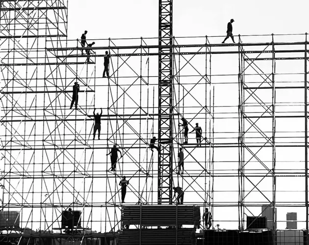 Cilvēki staikā pa sastatnēm