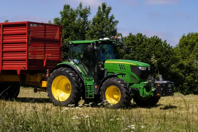 John Deere traktors ar sarkanu piekabi